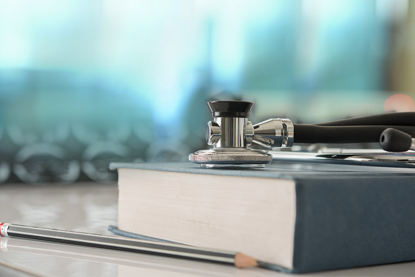 Stethoscope with medical text book on doctor student desk at classroom in the hospital.